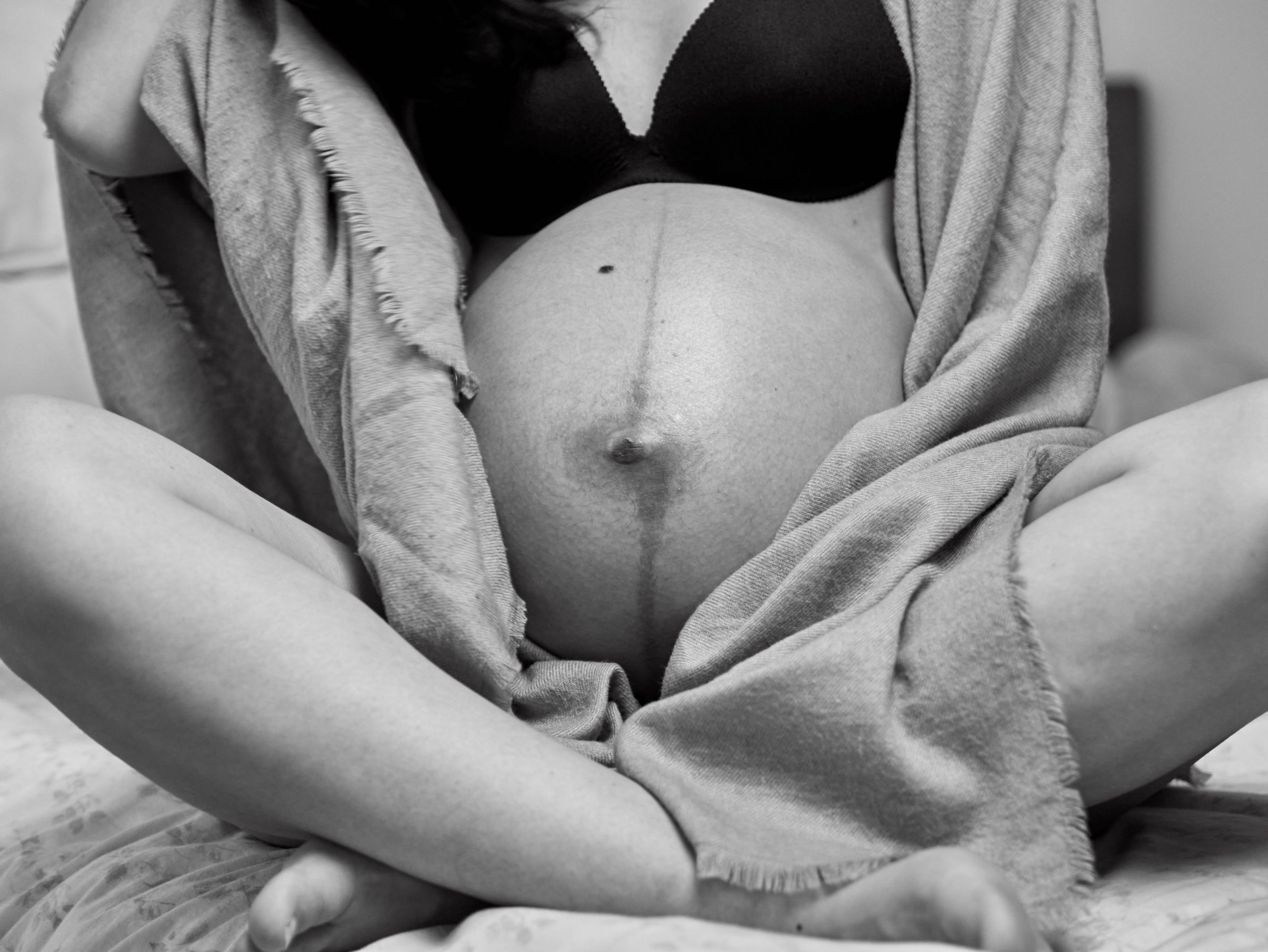 Artistic black and white maternity photo showing a pregnant woman's belly.